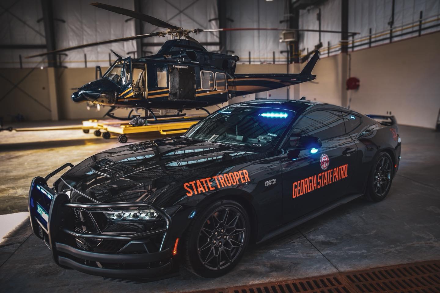 Georgia State Patrol Mustang police vehicle and helicopter inside an aviation hangar