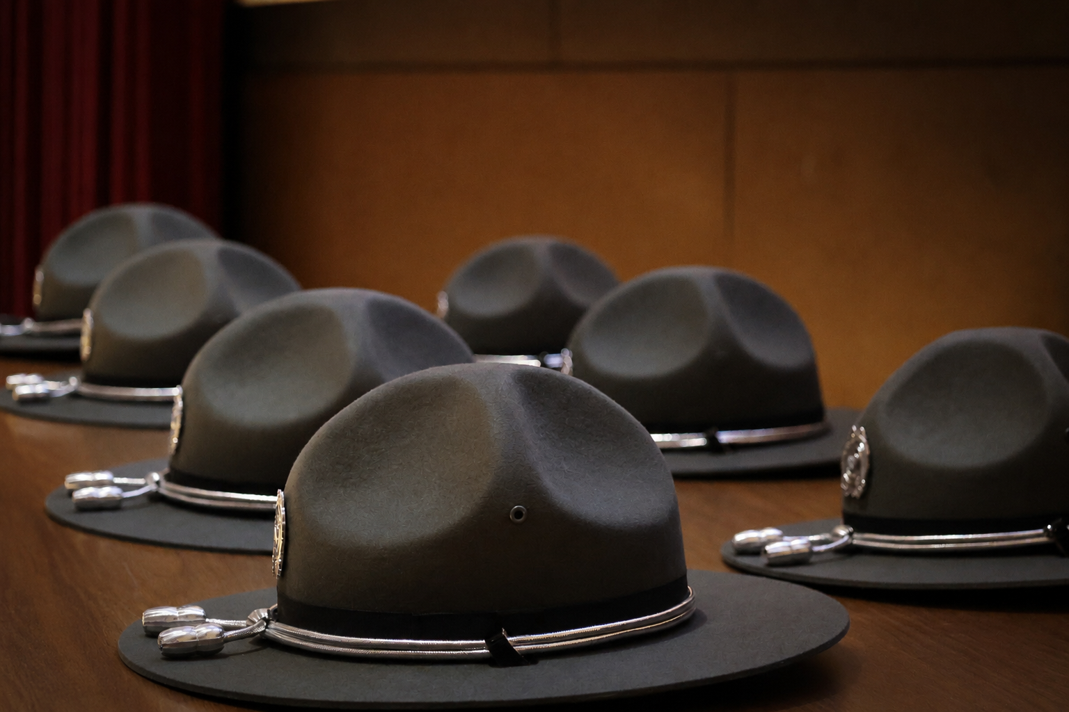 Row of Georgia State Patrol campaign hats lined up on a table before a graduation ceremony. 