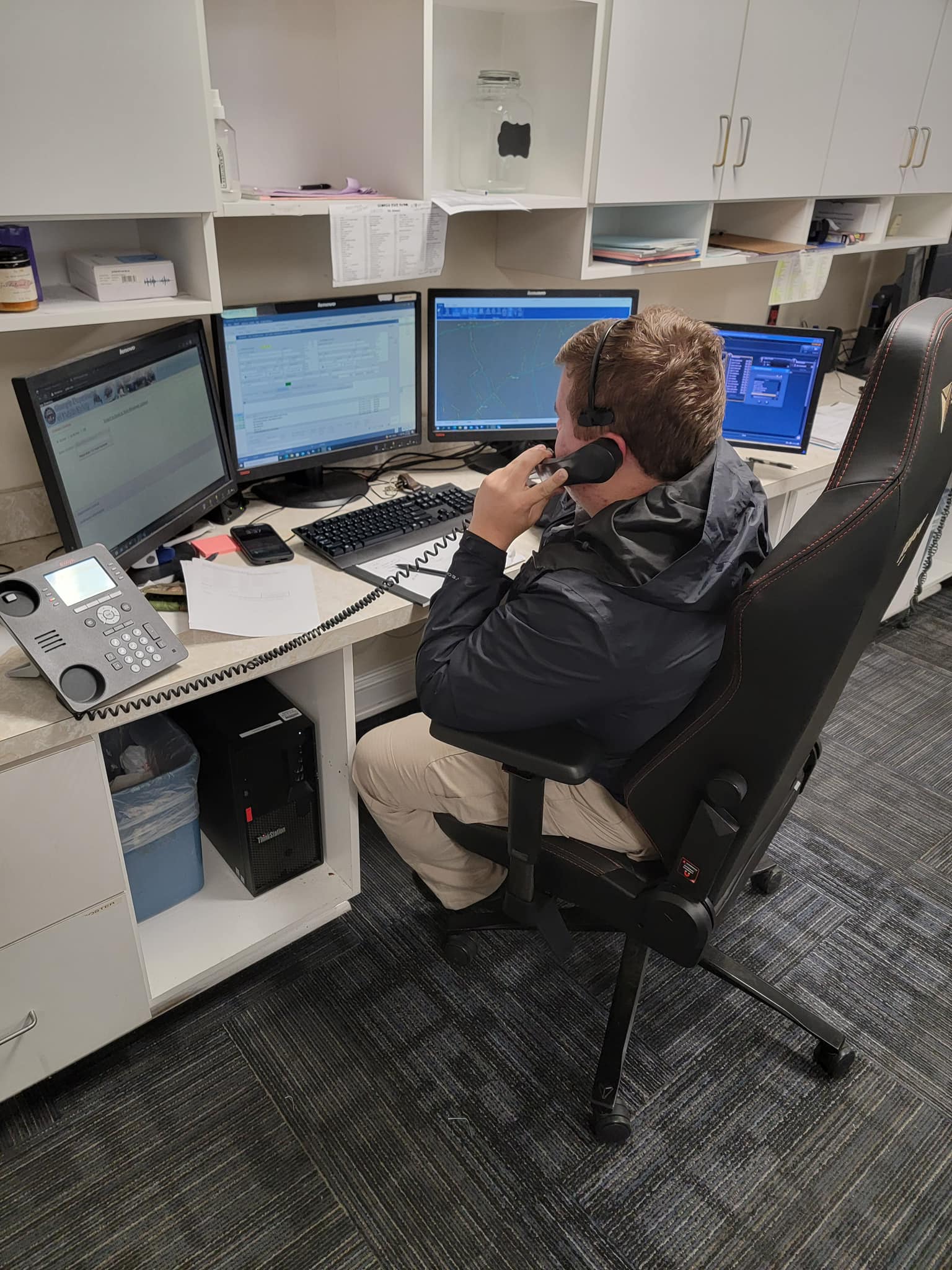 DPS dispatcher at workstation managing multiple screens and radio communications
